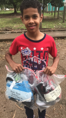 Honduran boy with two bags of clothes and shoes.
